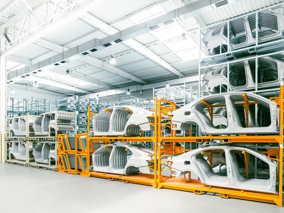 Car hulls in an early production stage, stacked in a manifacturing facility.