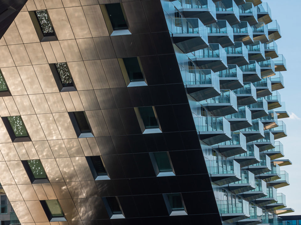 The ground and the sky are reflected in the aluminum façade of the Sluishuis building.