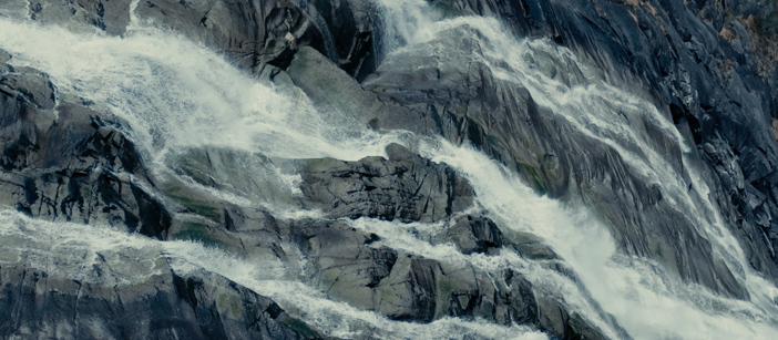 Ein Wasserfall, der entlang einer steinigen Bergwand fließt.