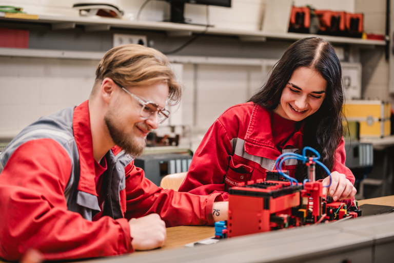 Two young Speira employees in work clothes work together on an appliance.