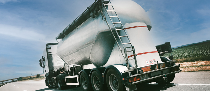 Back side of a truck with an aluminium shell standing in front of a blue sky.