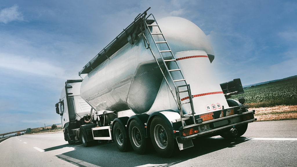 Back side of a truck with an aluminium shell standing in front of a blue sky.