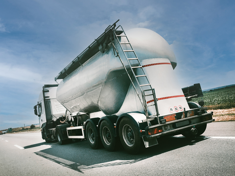 Back side of a truck with an aluminium shell standing in front of a blue sky.