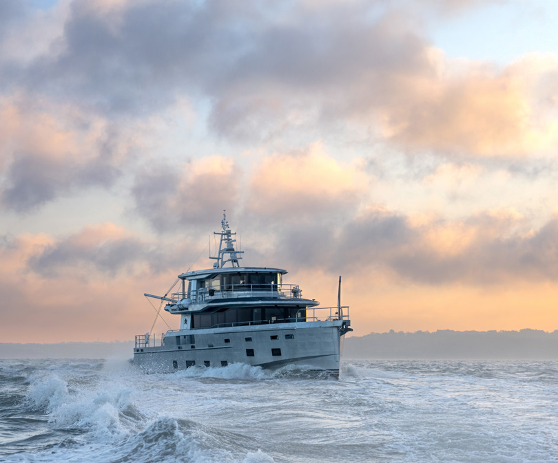 Arksen 85 Explorer Yacht on the sea in front of a sunrise.