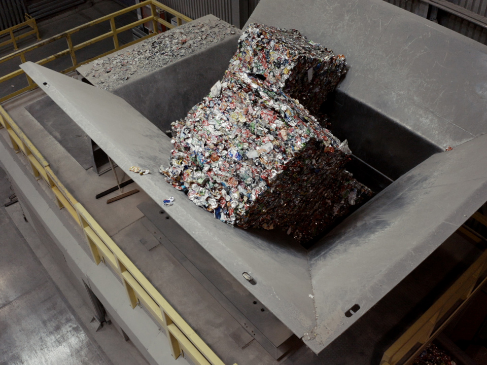 Bales of compressed aluminum cans stacked in a recycling facility.