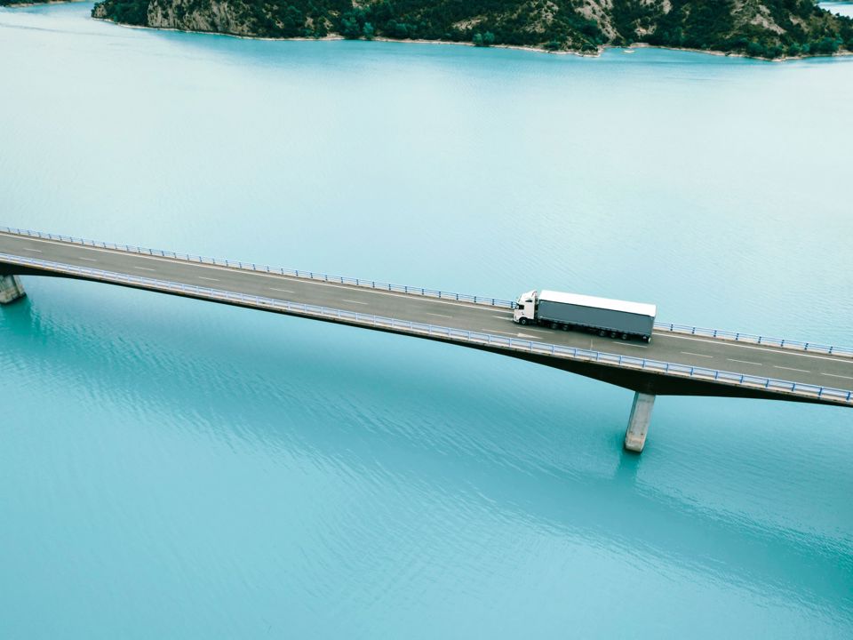 A truck drives over a bridge that crosses a body of water.