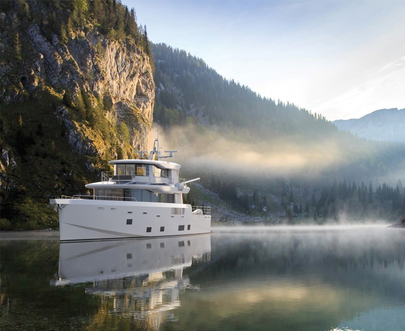 Arksen 85 Explorer Yacht auf dem Wasser vor Bergen und Bäumen.