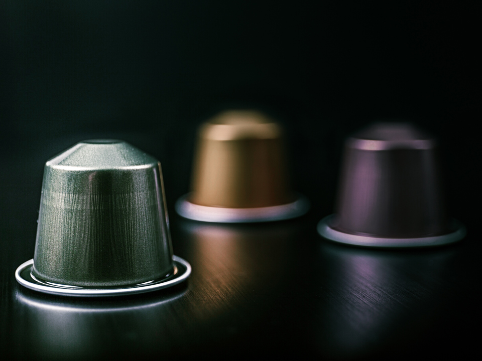 Close up of coffee capsules made of aluminium lying on a table.