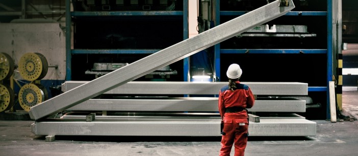 Speira employees in work clothes in front of an aluminum bar that is being lifted.