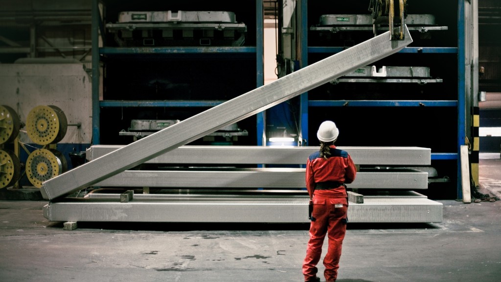 Speira employees in work clothes in front of an aluminum bar that is being lifted.