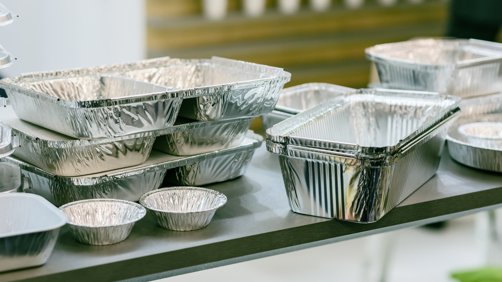 Sammlung von mehreren unterschiedlich geformten Lebensmittelverpackungen aus Aluminium.