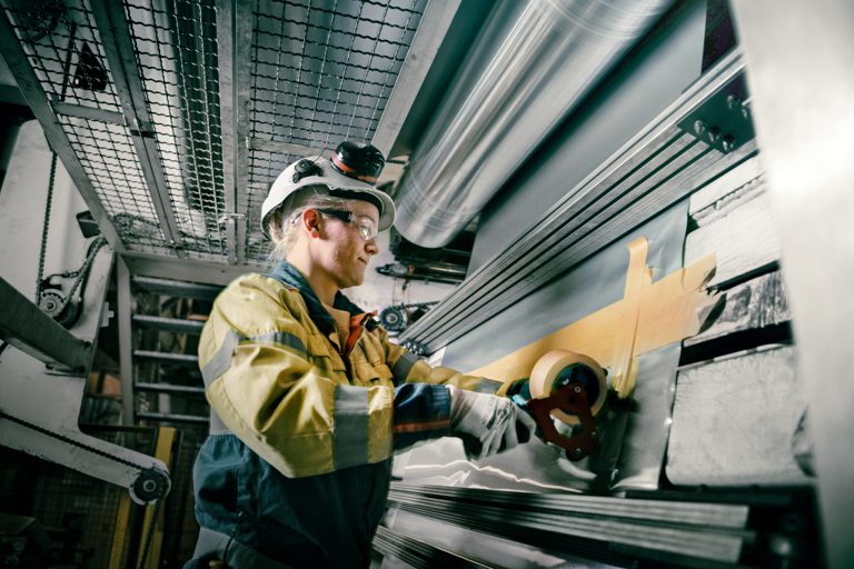 Speira employee during a production stage next to an aluminium coil.