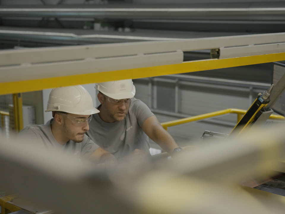 Two Speira employees inspect aluminum sheet for further production.