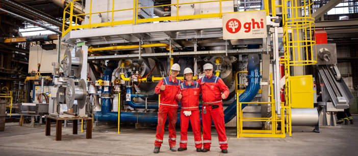 Three Speira employees in workwear stand in front of a new oven in Speira’s plant in Hamburg.