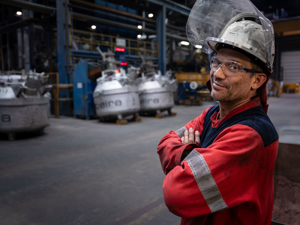 A smiling employee stands in work clothes at a Speira plant.