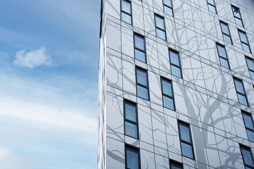 Aluminum façade of Kelaty House with decorative elements on a sunny day.