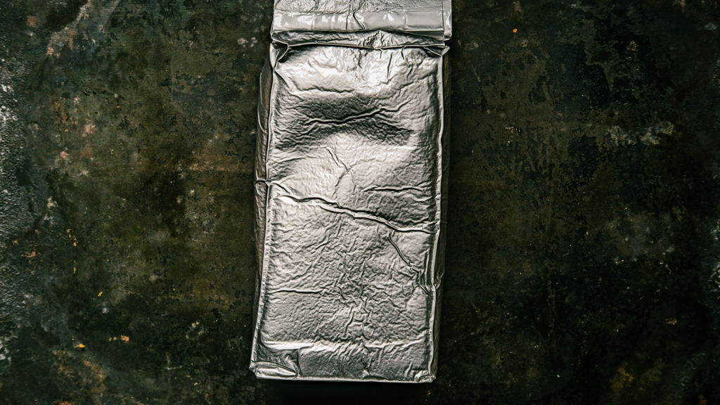 An aluminium package lying on a concrete surface.