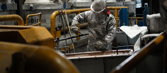 Speira employees in heat-protective clothing during an aluminum production phase.