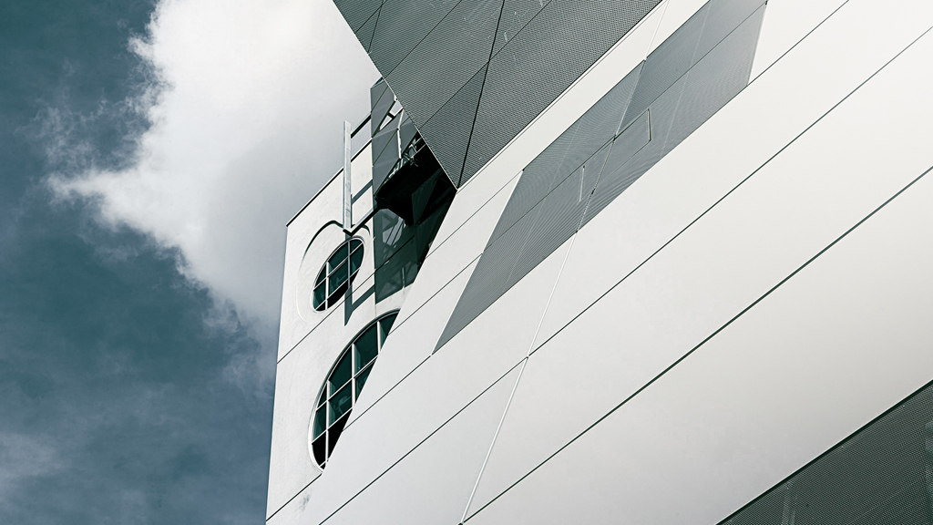 White aluminium panel façade of a building reflecting the sunlight.