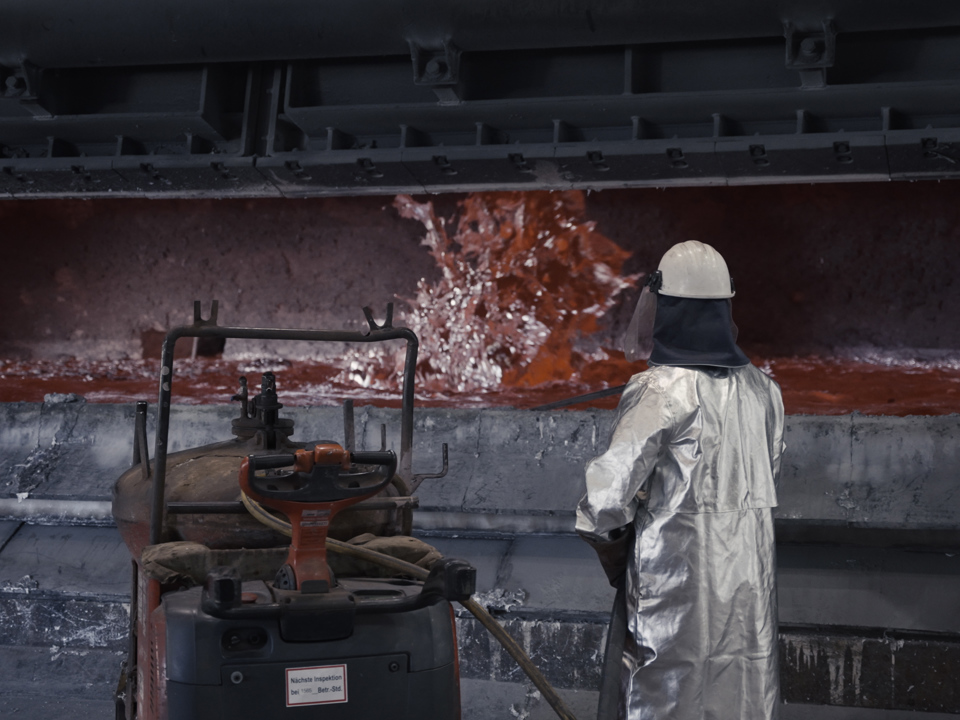 A Speira employee in front of an active furnace in the aluminum plant.