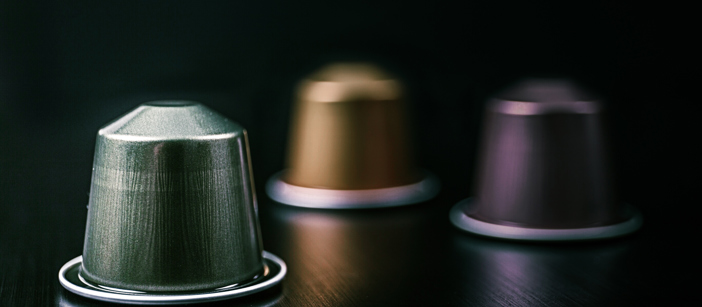 Multicolored aluminium coffee capsules on a black surface.