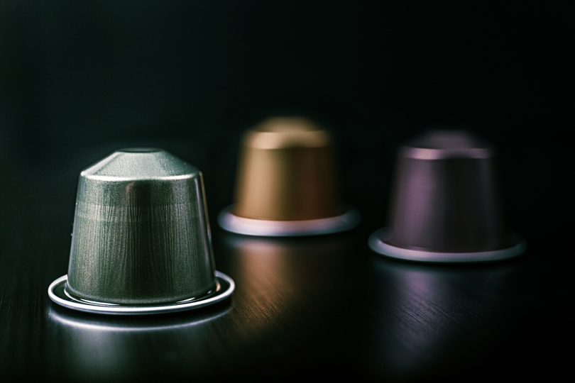 Multicolored aluminium coffee capsules on a black surface.