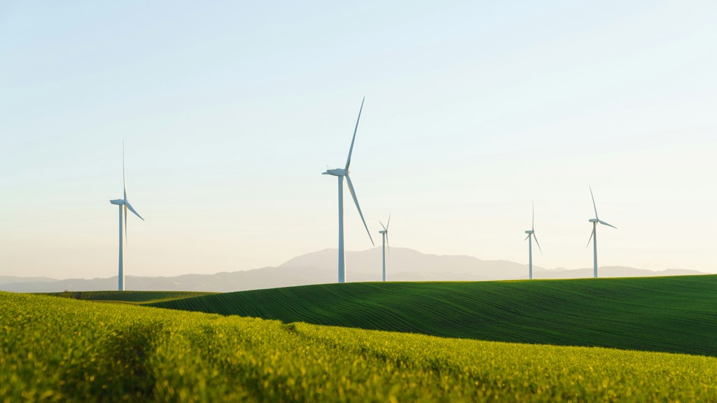 Wind turbines standing in a grassy field landscape on a sunny day.