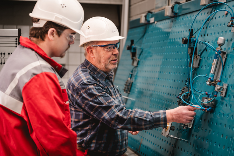 A Speira employee explains something about a technical device to a younger colleague.