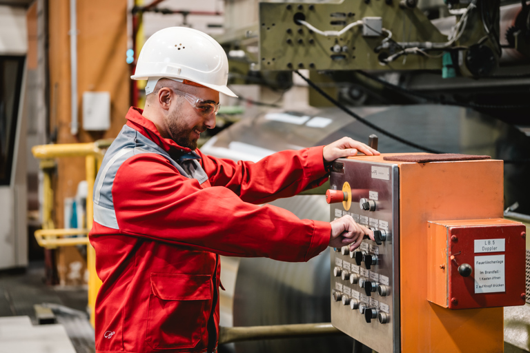 A Speira employee in work clothes operates a system in one of the plants.